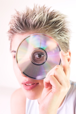 Blond short hair woman woman with white Tshirt looking through a CD holeの写真素材