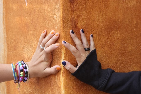 hands of teenager girls on a orange wallの写真素材