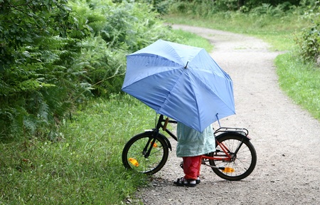 child on  a bicycle with a blue umbrellaの写真素材