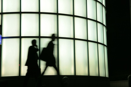 Silhouette passing by lighted windowsの写真素材