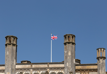 Union Jack flag flying over castle roof with a blue sky.の写真素材