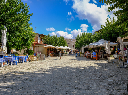 Omodus, Cyprus - September 30, 2017: Omodus Monastery of the Holy Cross, Abbot Dositheos statue.  Found at the entrance to the Monastery., 2017: Omodus centre with cobbled street and restaurants each side of the street.  Summer shot with tourists.のeditorial素材