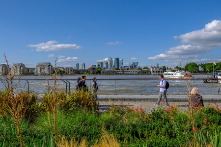 GREENWICH, LONDON, UK - AUGUST 10TH, 2017: Canary Wharf and River Thames with colourful flower beds in the foreground.のeditorial素材