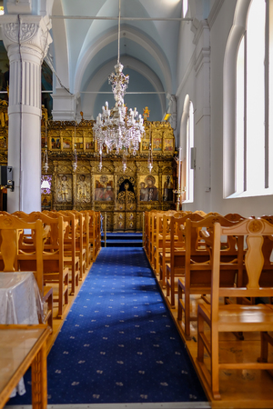 Nicosia, Cyprus - May 14, 2018: Side alter in the Holy Mary Church in Nicosia.  Shows the aisle with chairs on either side and icons on the wall in the background.のeditorial素材