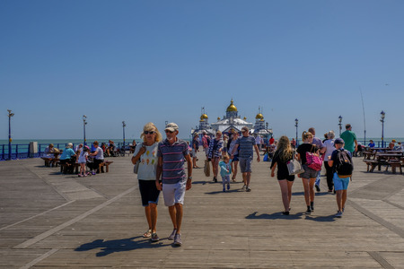 Eastbourne, Sussex, UK - August 1, 2018: People strolling on the pier at Eastbourne.  Taken on a bright sunny blue sky summer's day.のeditorial素材