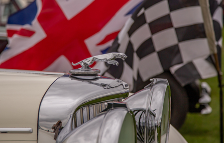 Enfield, Middlesex, UK - May 24, 2015: Closeup shot of the front of a vintage Jaguar car with lots of shiney chrome and flags in the background.のeditorial素材