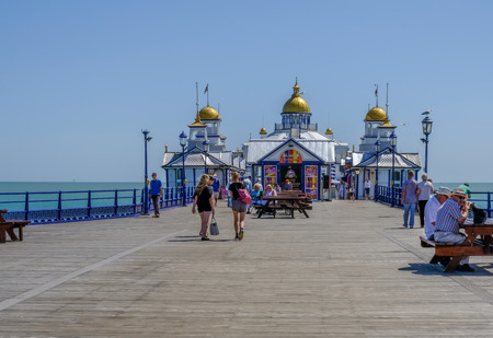 Eastbourne, Sussex, Uk - August 1, 2018: View of the end of the pier with people strolling and sitting at picnic tables.  Taken on a beautiful sunny summer's afternoon.のeditorial素材