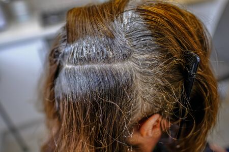 Close up shot of dark hair having the roots coloured. A parting with tint applied.