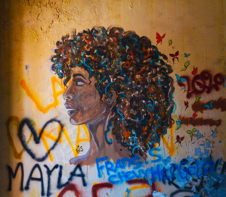 Beautiful African American woman with curly hair and colorful graffiti on the wallの写真素材