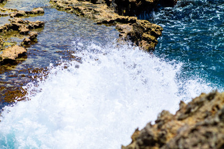 Waves of the sea breaking against the rocks on the island of CuraÃ§aoの写真素材