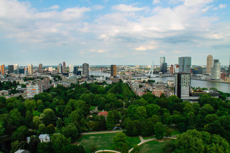 A panoramic view of a city skyline featuring modern skyscrapers, green parks, and a river. The scene captures a blend of urban architecture and nature under a partly cloudy sky.の写真素材