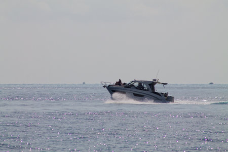A sleek motorboat cruising on calm waters, leaving a trail of white foam. The scene is serene with a...