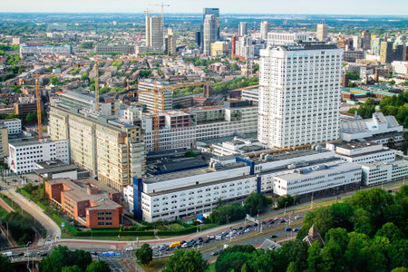 Aerial view of a modern urban landscape featuring a mix of high-rise buildings and low-rise structures, surrounded by greenery and roads.の写真素材