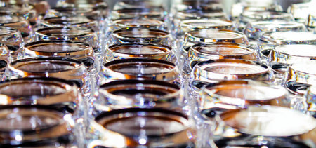 A close-up view of numerous glass jars arranged in a grid pattern, showcasing their shiny surfaces and reflections. The jars have a modern design and are filled with a light-colored substance, possibly a cosmetic or food item.の写真素材