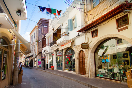 RETHYMNO, CRETE, GREECE â€” JULY 16, 2014: Shopping street decorated with colorful flags with a...