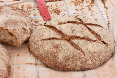 Freshly baked traditional Majorcan brown bread (pan moreno) on the table covered with tablecloth. Sineu market, Majorca, Spainの写真素材