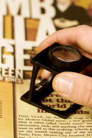 Hand holding a loupe proffing magazine or newspaper print.  up close and personal shot, getting the details right, doing a good job for your company.の写真素材