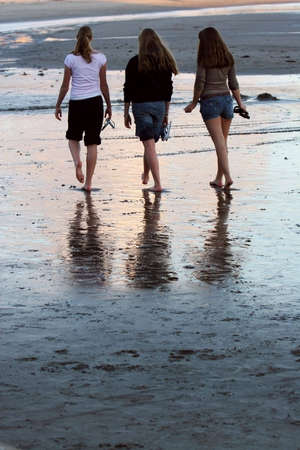 Girls taking a walk on the beach at sunsetの写真素材