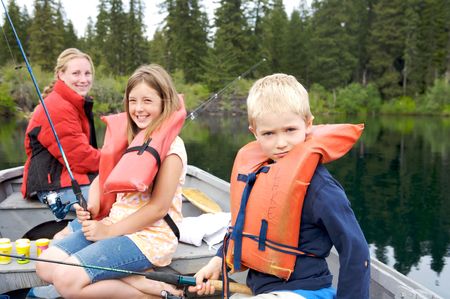 Three children fishing together on a lake, focus on the young boyの写真素材