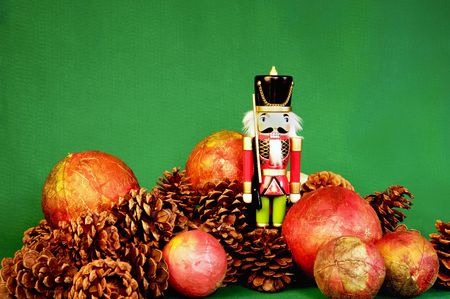 Nutcrack with pnecones and red ball ornaments on rustic green backgroundの写真素材