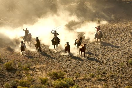 Two Cowboys galloping and roping through the desertの写真素材