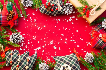 Gift with green branches of a Christmas tree, cones, toys and confetti on a red background. Flat lay. Copy space.の写真素材