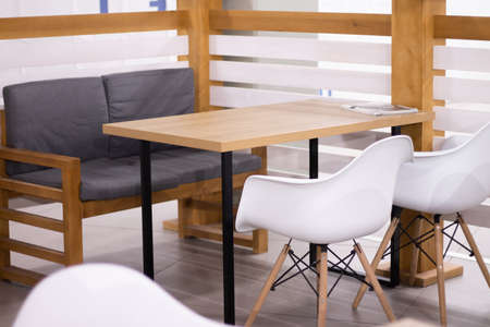 Gray sofa and white chairs near a wooden table in a small cafe in a shopping centerの写真素材