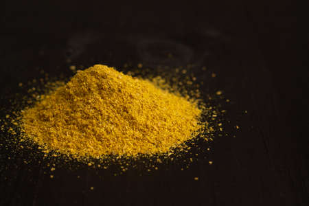 A slide of yellow turmeric or curry spice powder on a black wooden surface, copy spaceの写真素材
