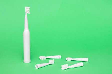 White wireless electric toothbrush with replaceable heads on a light green background, copy spaceの写真素材