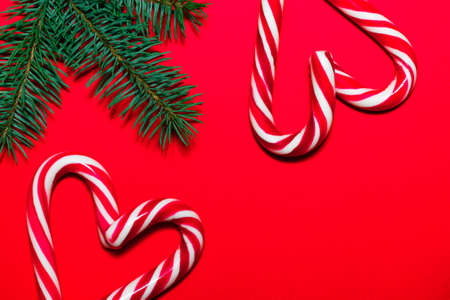 Lollipop hearts on red surface with Christmas tree branches. Christmas and New Year greeting cardの写真素材