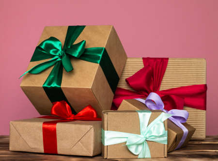 Gifts in craft paper with colorful ribbons on a pink backgroundの写真素材