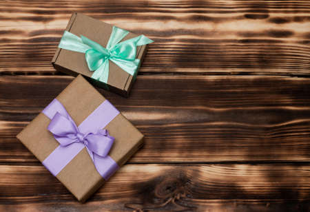 Gifts in craft paper with a lilac and mint ribbon on a rustic burnt wood background. Top view. Copy spaceの写真素材