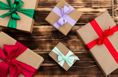 Gifts in craft paper with colorful ribbons on a rustic burnt wood background. Top viewの写真素材