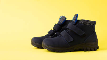 Dark blue autumn men's children's boots on a yellow background, copy space. Bannerの写真素材