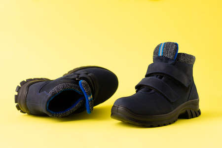 Dark blue autumn men's children's boots on a yellow background, copy spaceの写真素材