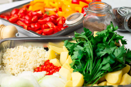 Chopped ingredients for making oriental vegetable stew. Paprika, potatoes, onions, tomatoes, garlic, peppers and spices.の写真素材