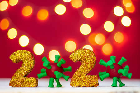 Golden glittering numbers 2020 with covid-19 virus with bokeh on red background. Copy space.の写真素材