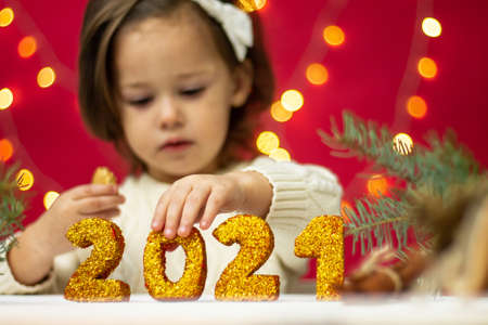 Little girl touching golden shiny numbers 2021, Merry Christmas and Happy New Year.の写真素材