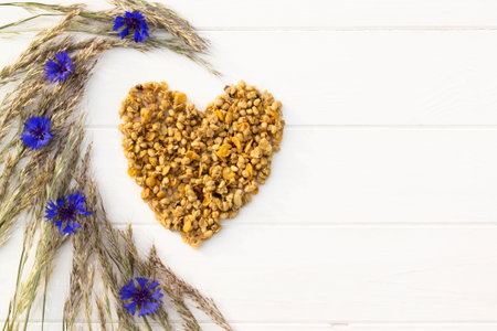 Heart laid out of granola, spikelets and cornflowers on a white wooden background. Flat lay. Copy space.の写真素材