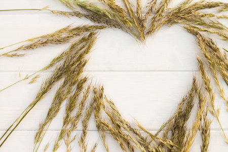 Heart laid out of spikelets on a white wooden background. Flat lay. Copy space.の写真素材