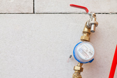 Cold water meter with a tap at the water inlet inside the house on the background of concrete blocks, measuring deviceの写真素材