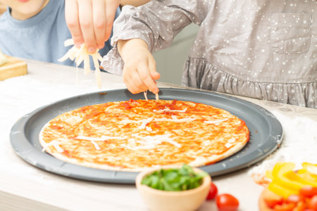 Hands of little girl in gray dress and boy cooking pizza together in kitchen, brother and sister cookingの写真素材