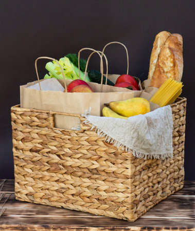 Fresh eco organic vegetables, greens and fruits, cereals and pasta in a wicker basket. Delivery or donation of ecological farm food conceptの写真素材