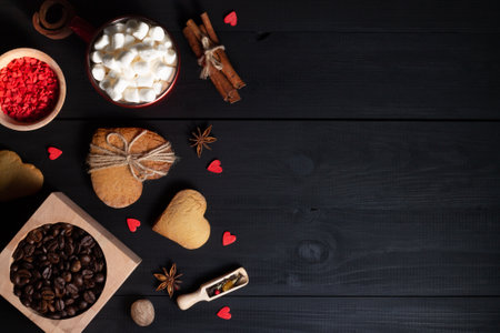 Gingerbread heart shaped cookies, spices, coffee beans and baking supplies on black wood background, copy spaceの写真素材