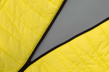 Stretched zipper lock of yellow jacket on gray background. Colors of the Year 2021   Illuminating and Ultimate grayの写真素材
