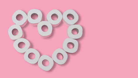 Heart made from rolls of toilet paper on a pink background. Valentines day during pandemic concept. Flat lay. Copy spaceの写真素材