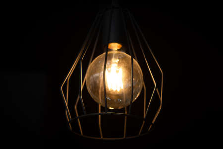Vintage edisson lamp with black forged wire lampshade, on dark backgroundの写真素材