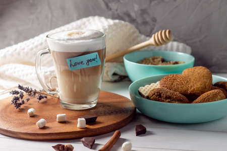 Coffee latte cup with Love you sticker on wooden tray with turquoise bowls with cookies and marshmallows on gray wall backgroundの写真素材