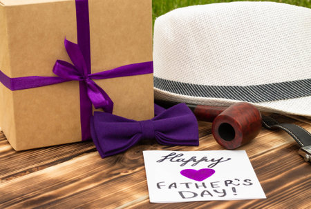 Greeting card Happy Father's Day with a gift box and men's accessories on a rustic wooden tabletopの写真素材