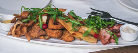 Long oval plate with variety of snacks: chips, nachos, bacon, lavash with cheese, arugula,...